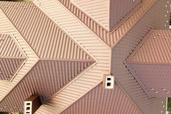 Aerial view of house roof structure covered with brown metal tile sheets.
